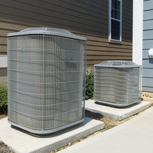 Two central air conditioner condensers on concrete pads beside a Los Angeles home