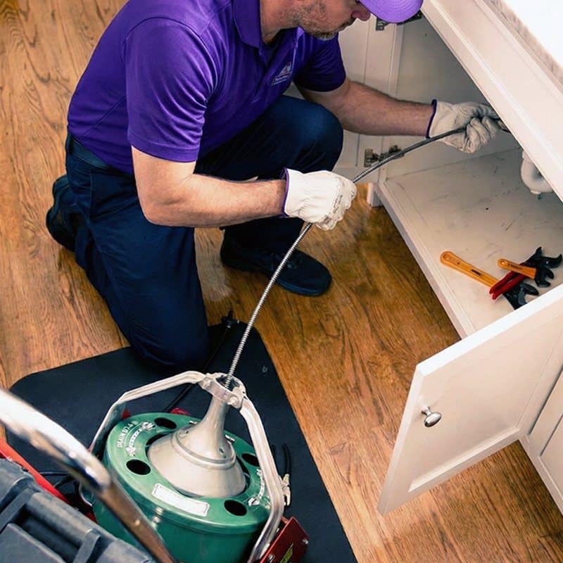 ServiStar technician snaking a kitchen drain under the sink