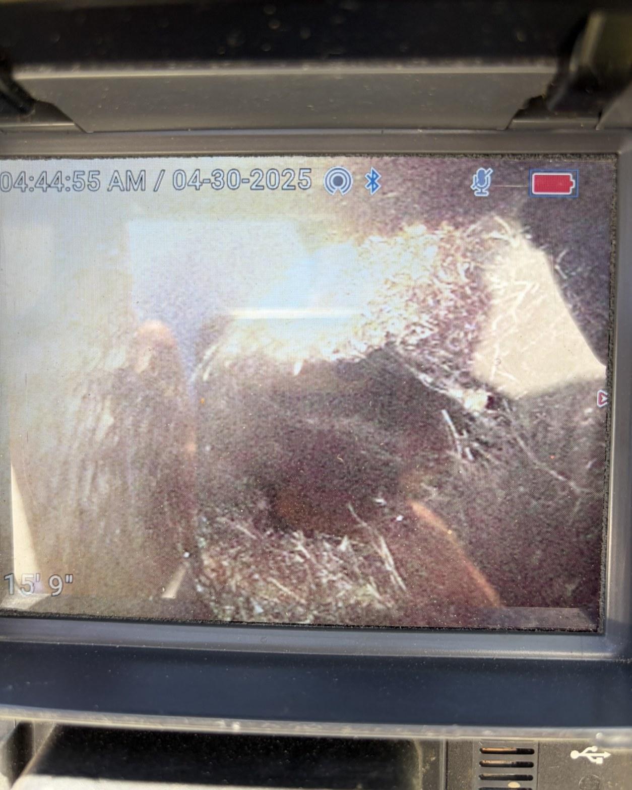 Push-camera monitor showing dense debris and root blockage at 15 feet 9 inches in a sewer pipe